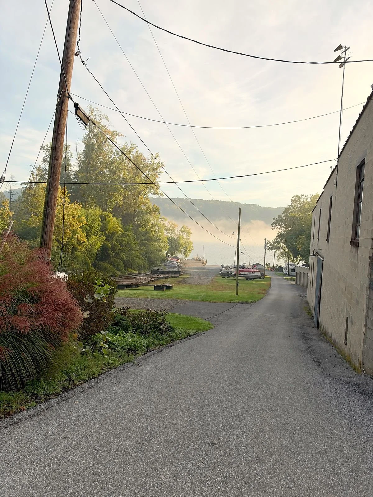 The road down to the boatyard, with boats and trailers and a misty river
