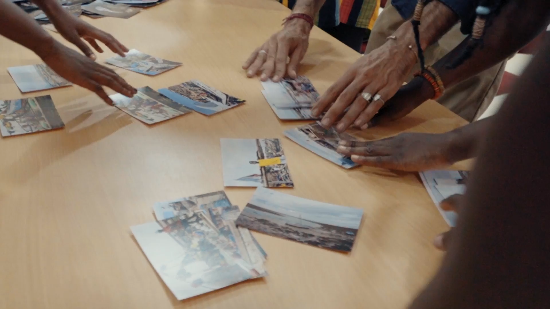 Hands examining and sharing historical photographs on a table.