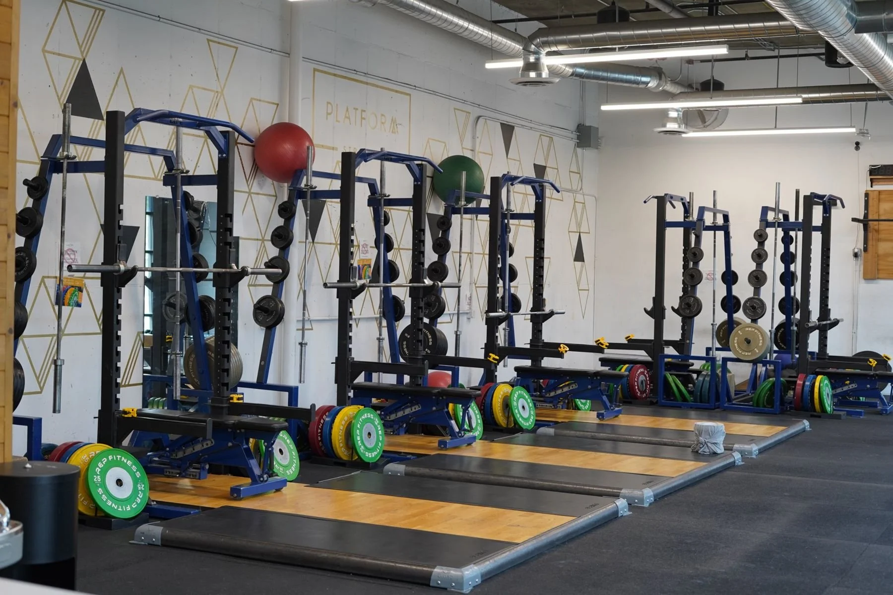 A row of squat racks and lifting platforms at Platform Strength