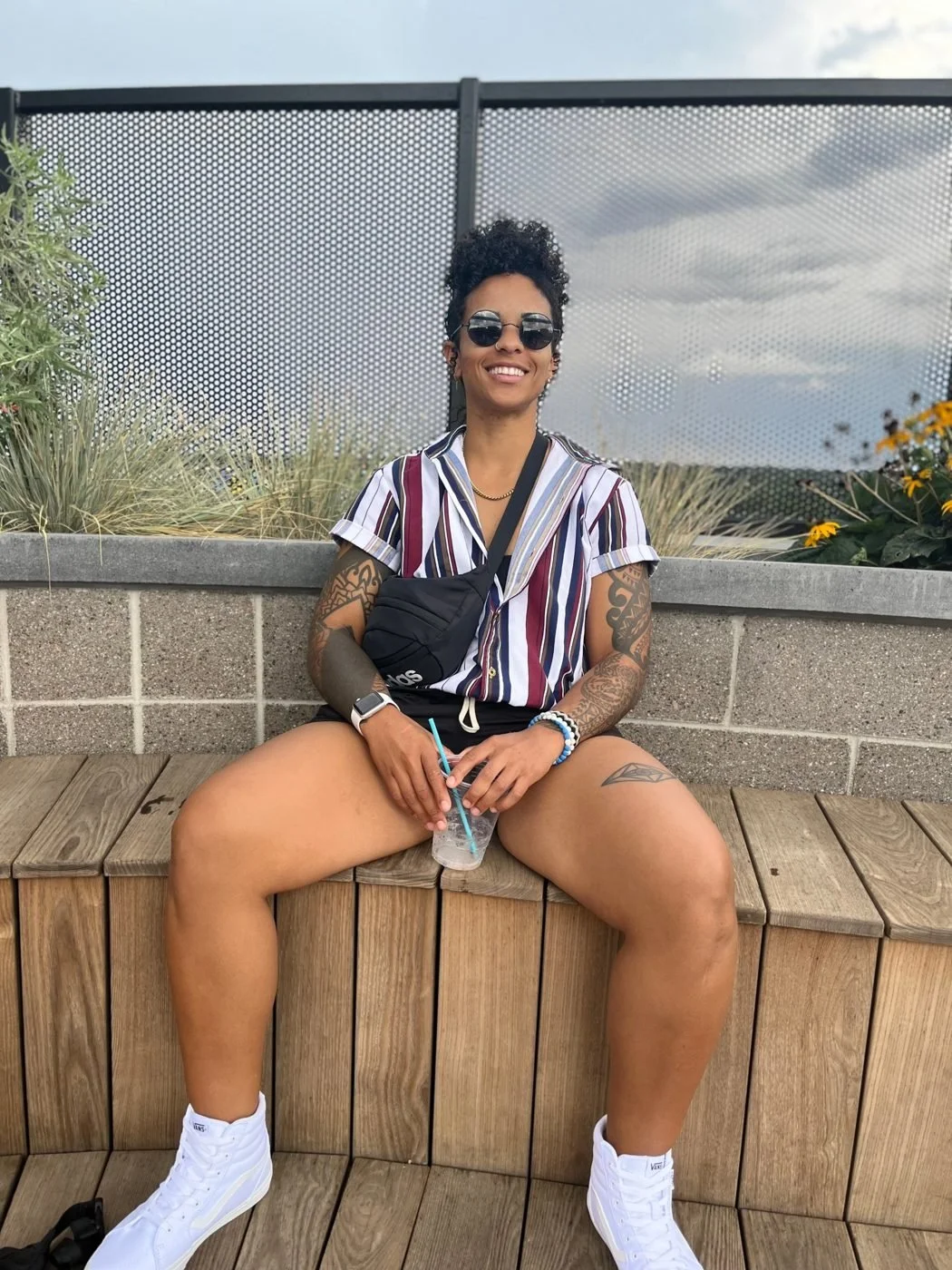 Coach April smiling on a sunny rooftop bench