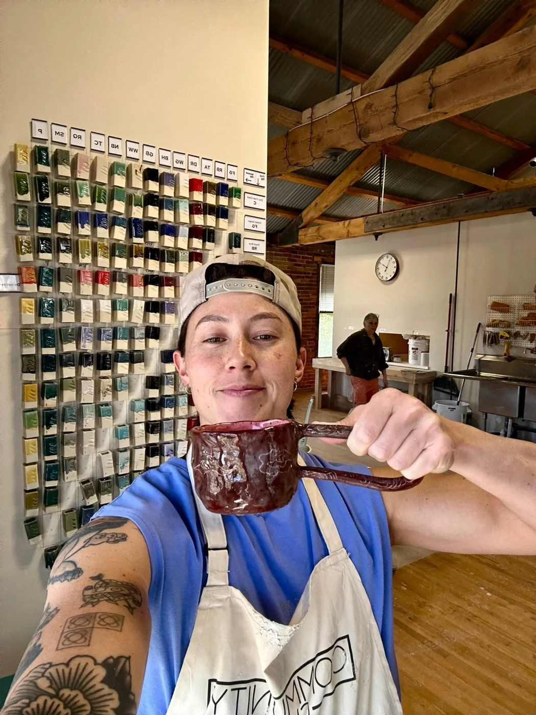 Coach Sav off the platform, holding a handmade mug at a pottery studio