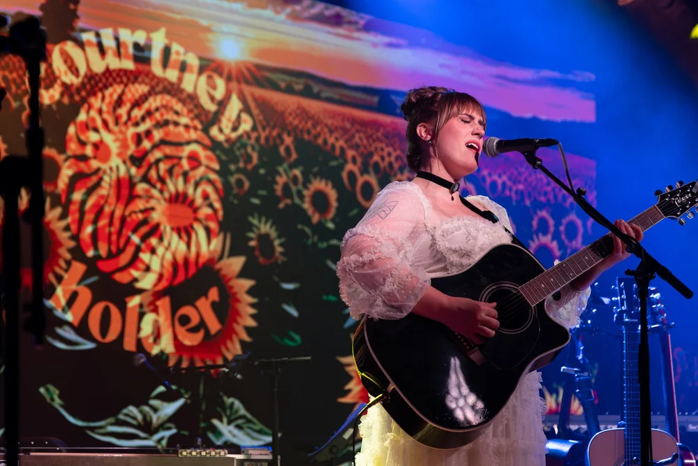 Singer-songwriter performing on stage with a guitar