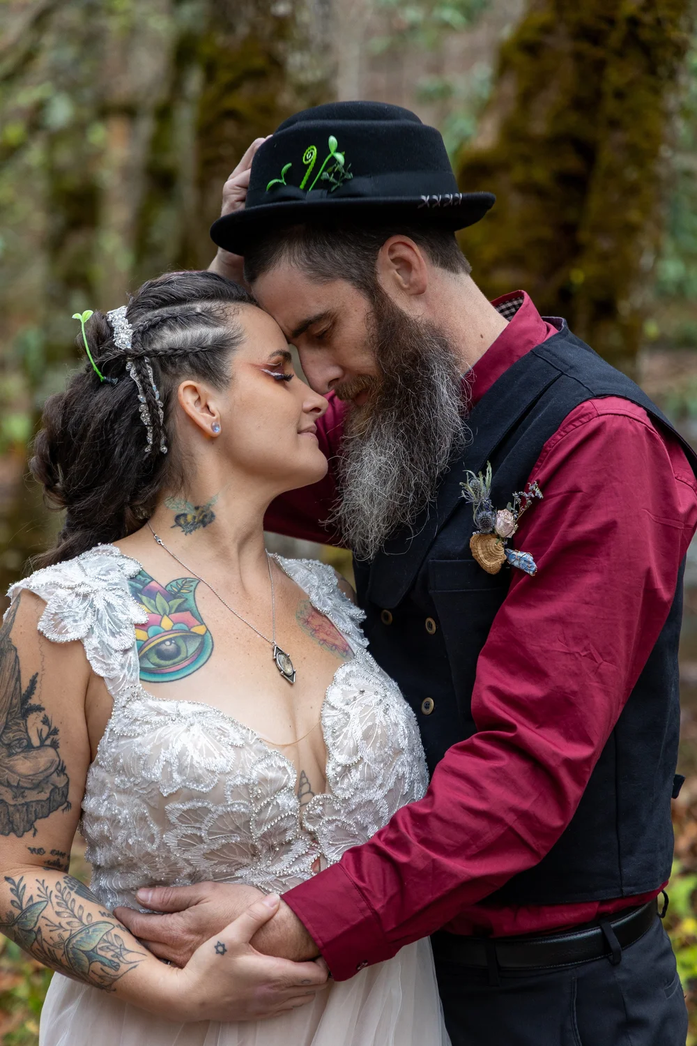 Bride and groom resting their foreheads together in a mossy forest