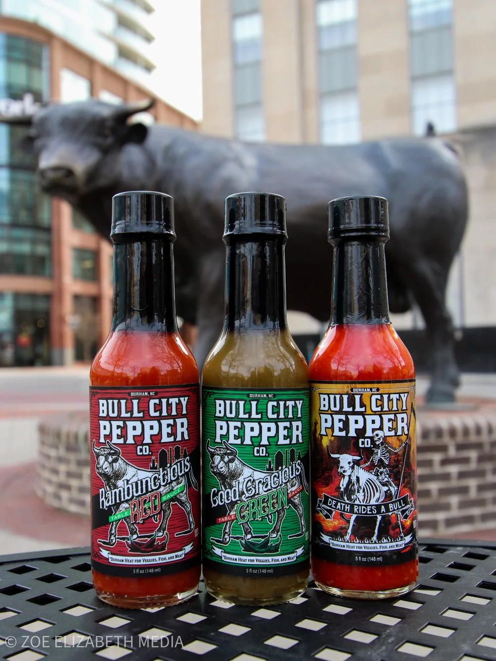Three bottles of Bull City Pepper Co hot sauce photographed on location downtown