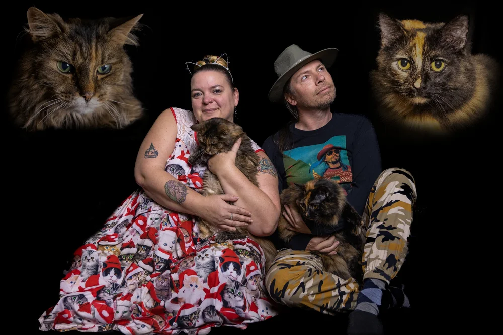 Couple photographed in studio with portraits of their cats