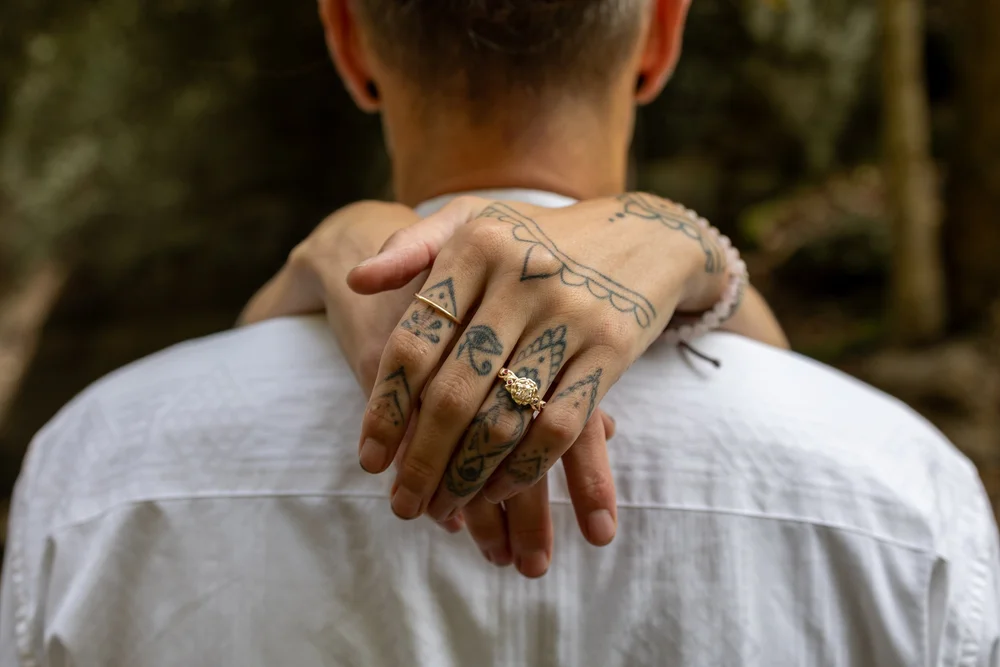 Close detail of a tattooed hand resting on a shoulder