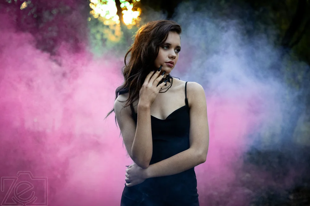 Portrait of a woman surrounded by pink and blue smoke