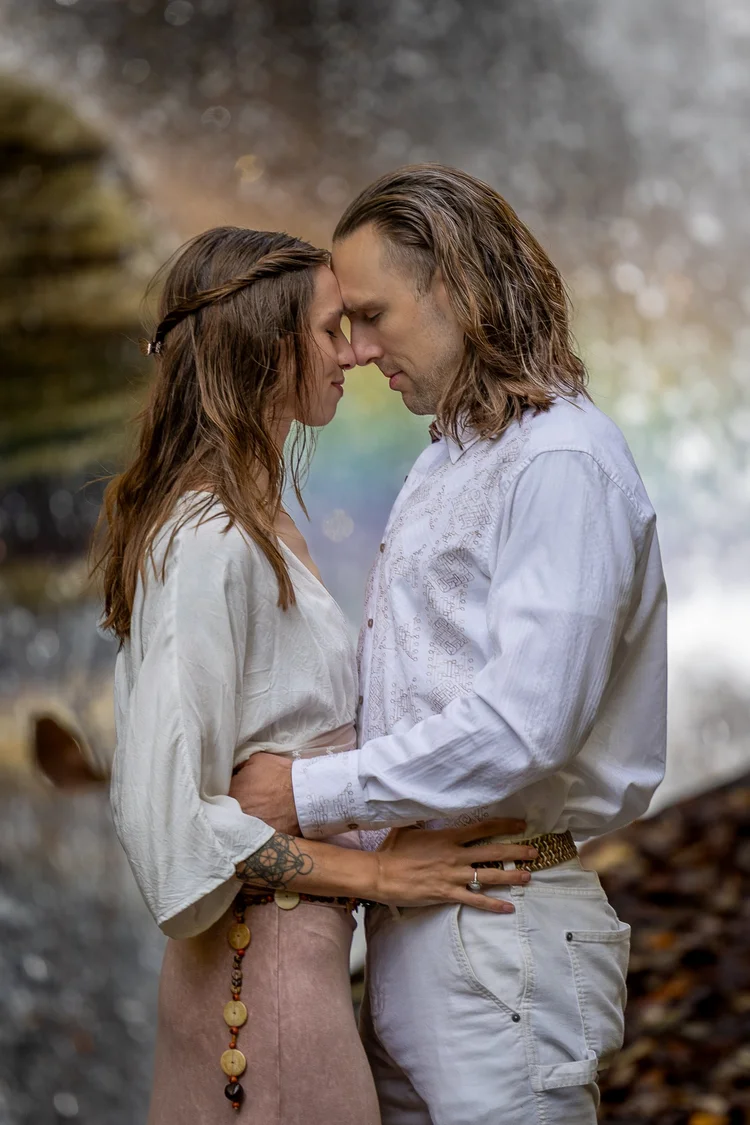 Engaged couple resting their foreheads together beside a waterfall
