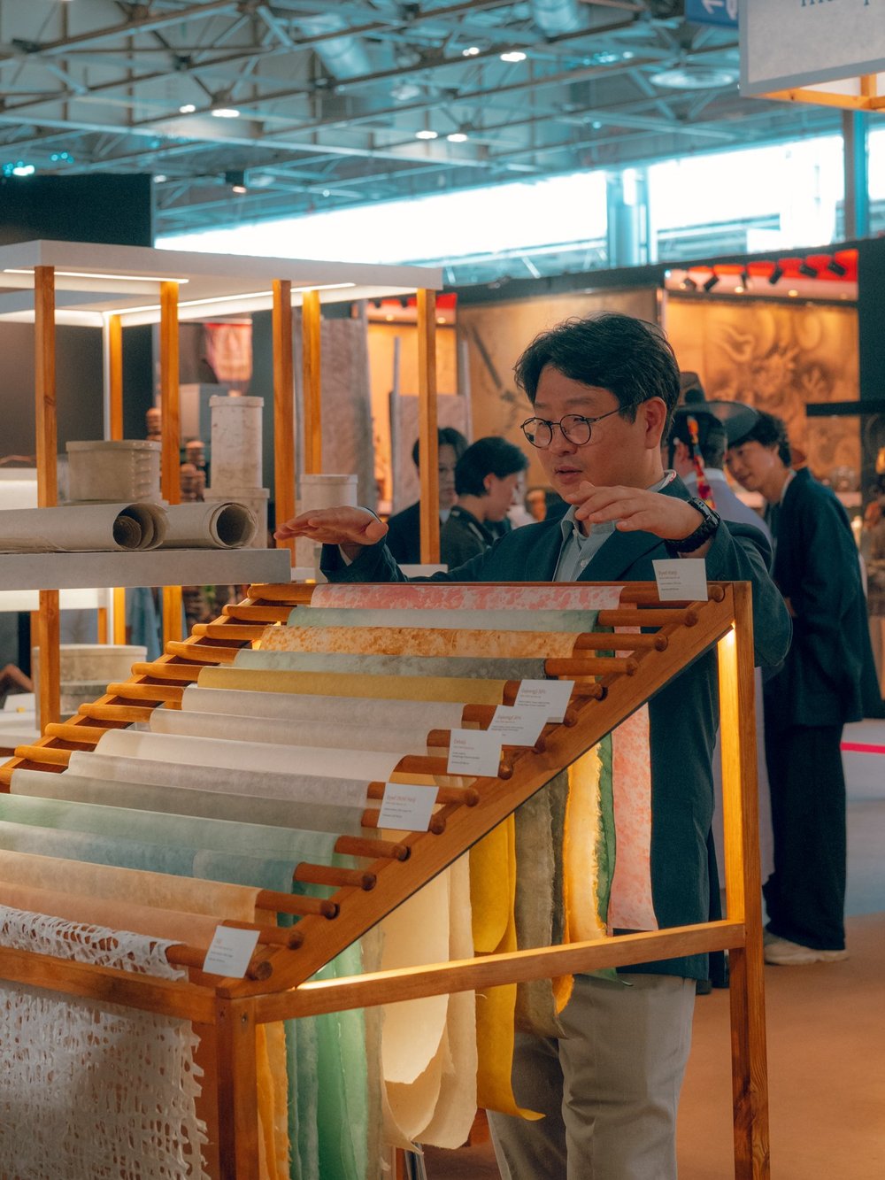 Visitor looking at translucent hanji sheets on a wooden display rack