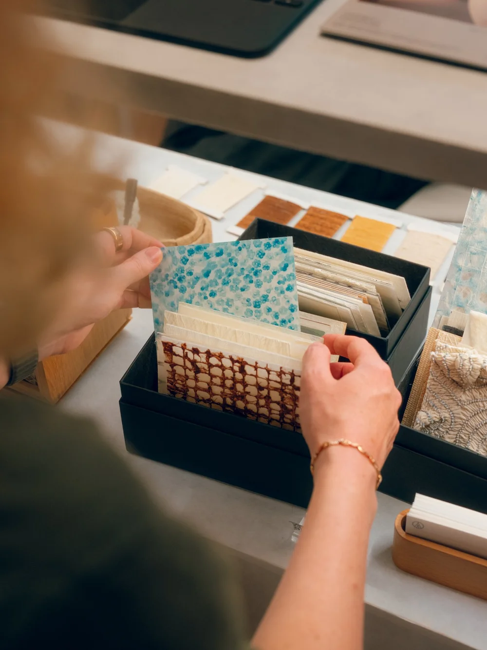 Hands leafing through a box of patterned Korean paper samples