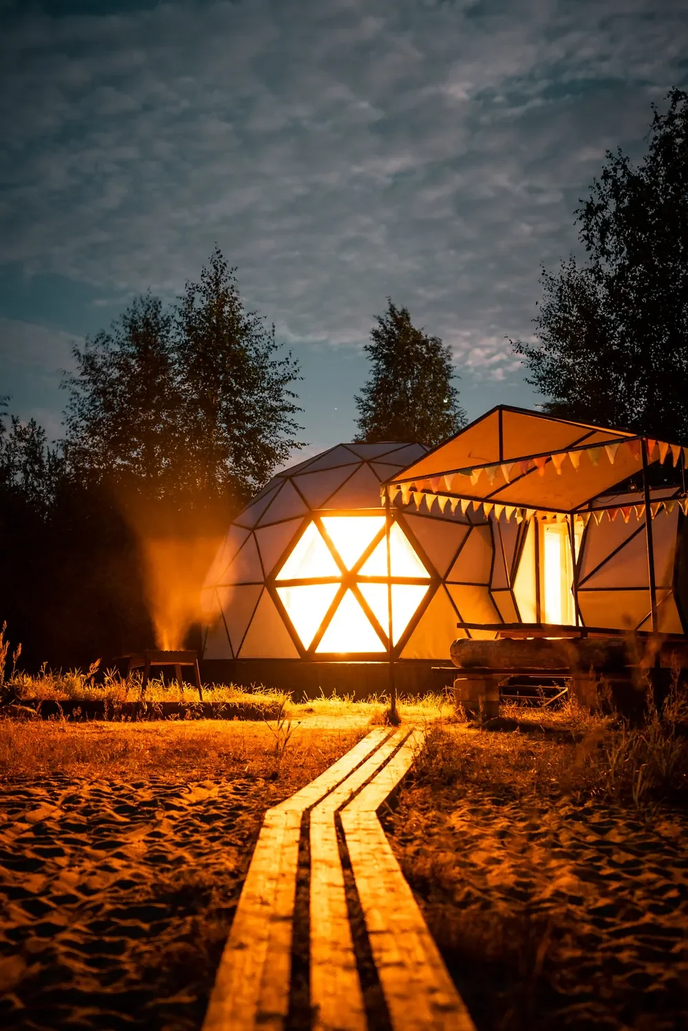 Wooden path leading to the illuminated Sfera dome at night
