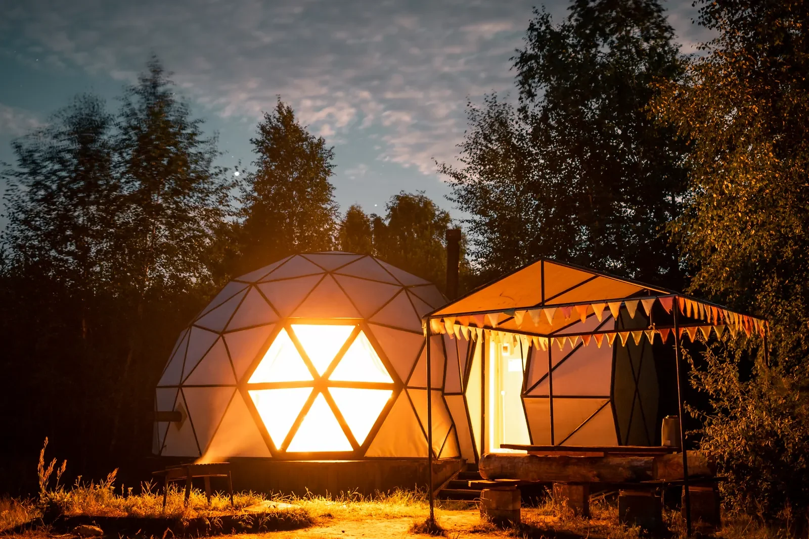 Sfera eco-camping dome glowing in the forest at night