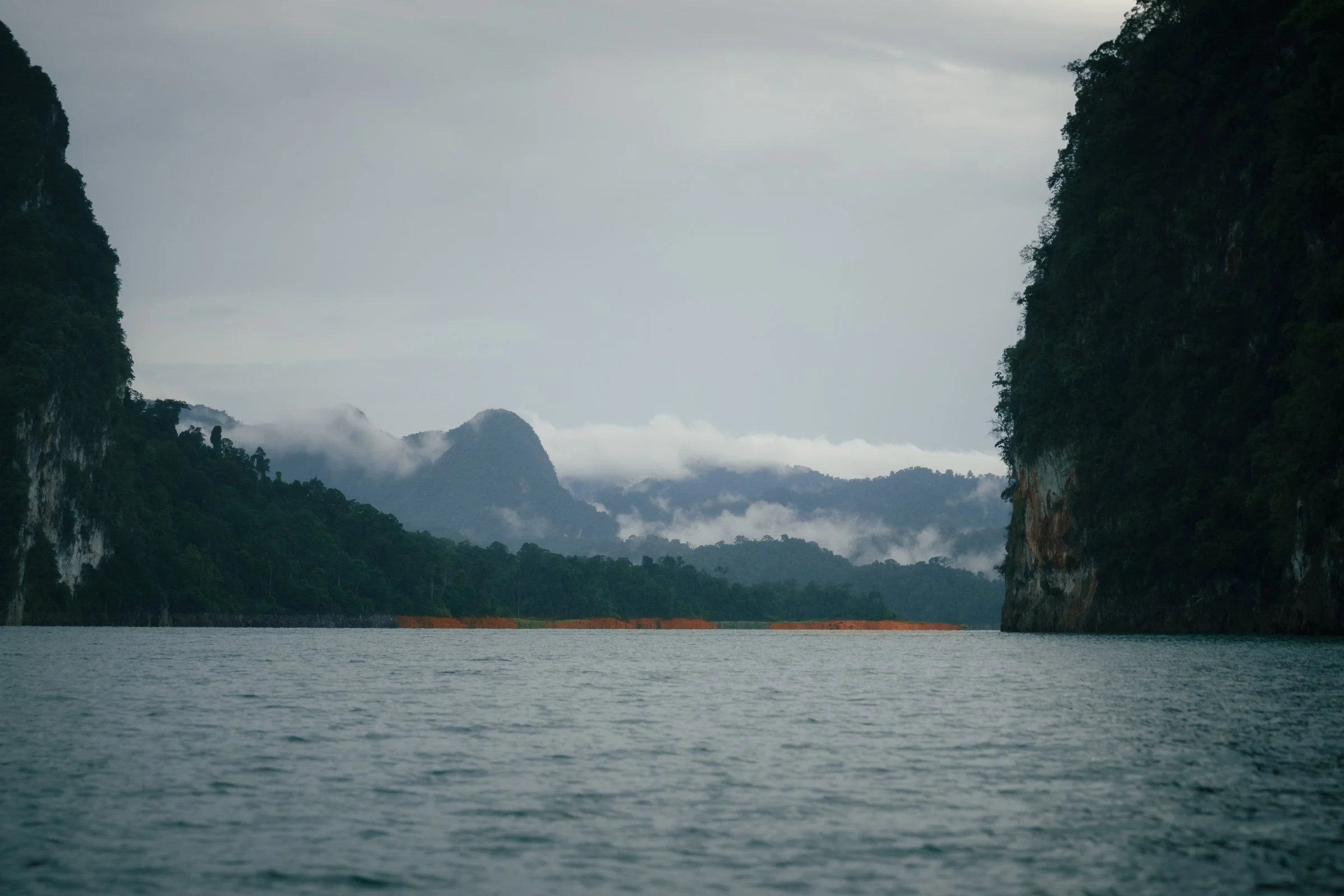 Misty limestone mountains above a quiet lake in Thailand