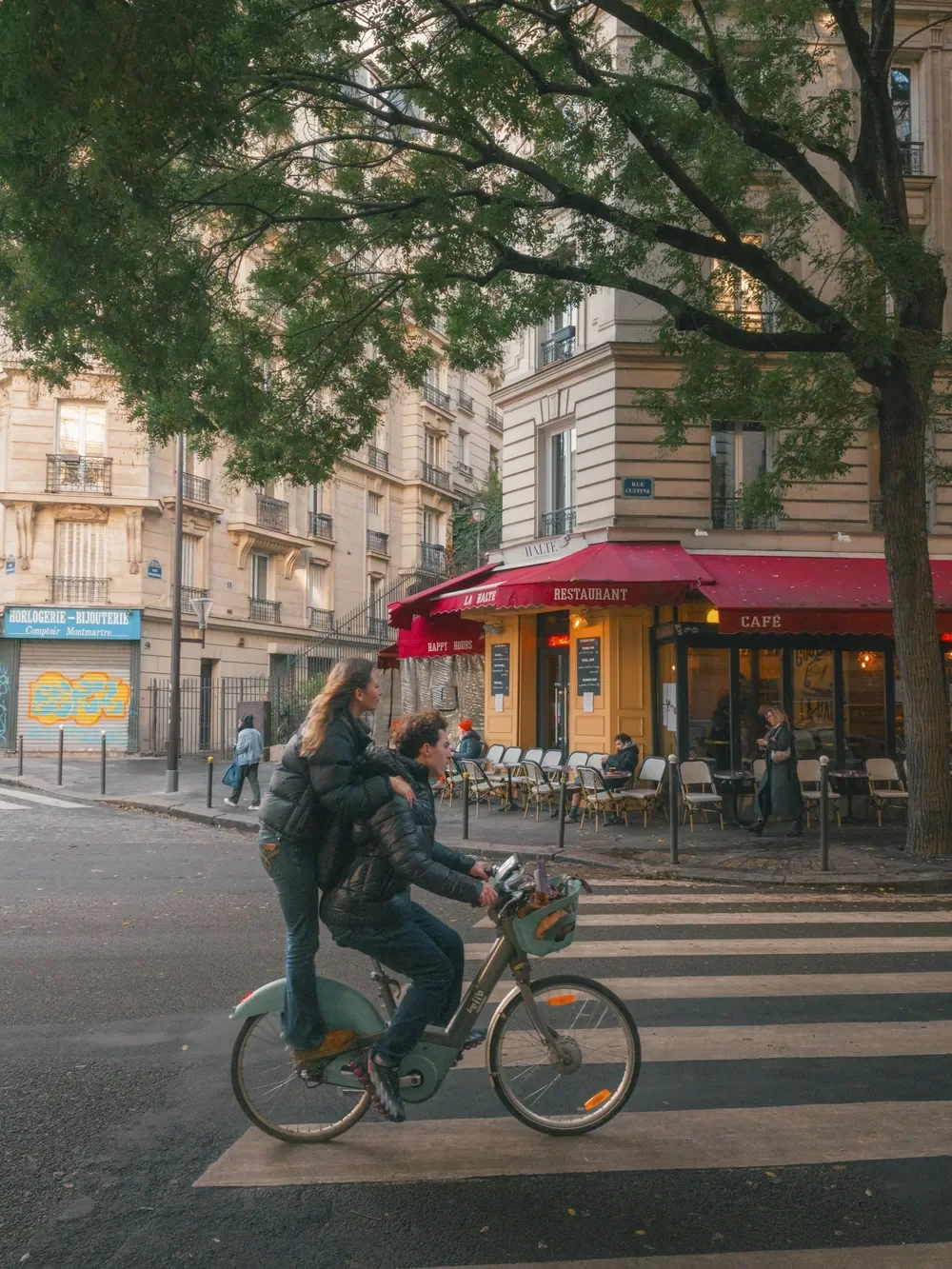 Cyclists crossing a Paris street beside a red café