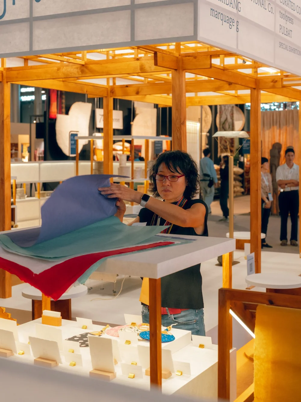 Visitors examining coloured paper at the HANJI HOUSE display table