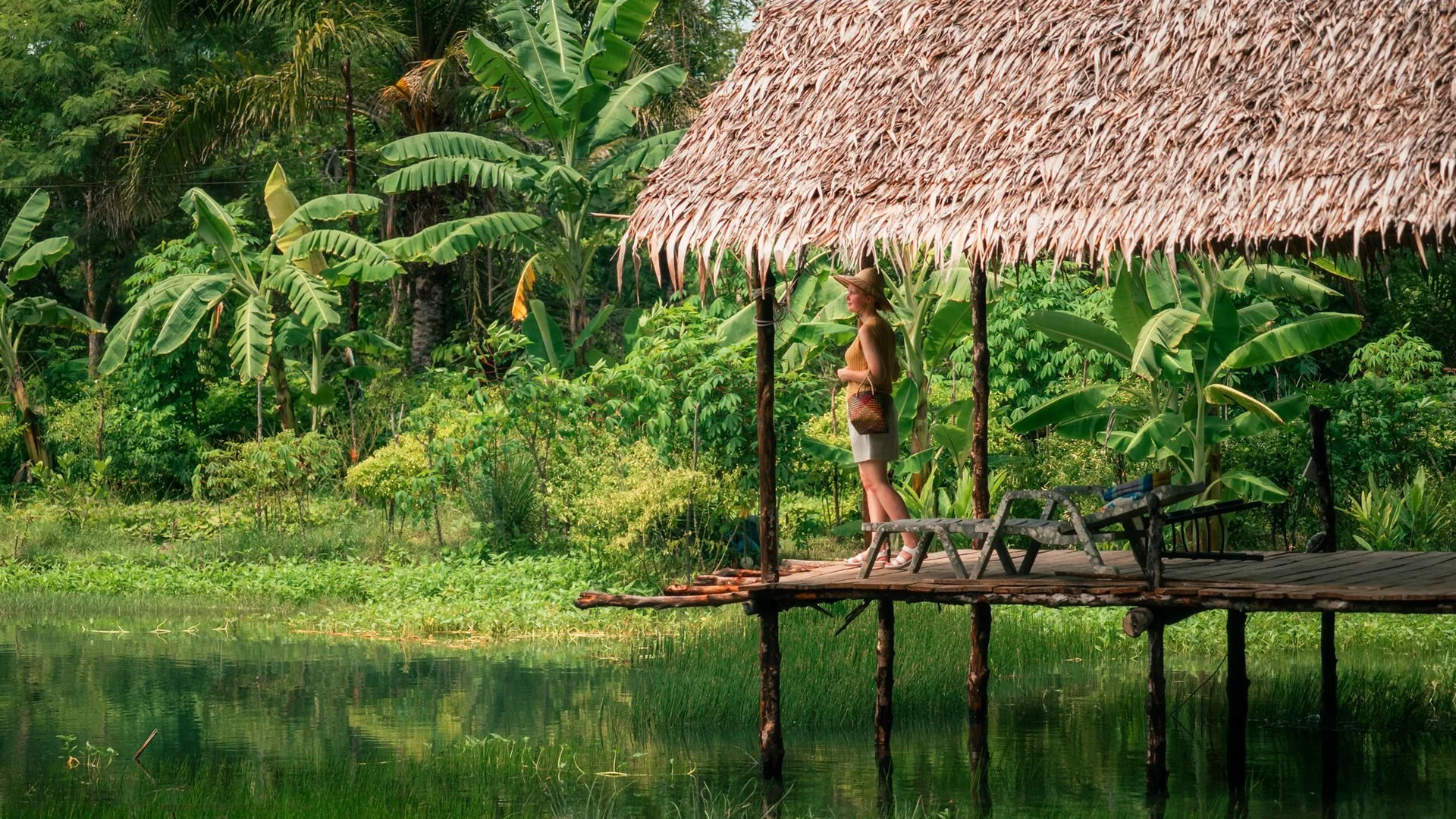 Traveller beside a tropical waterside shelter in Thailand