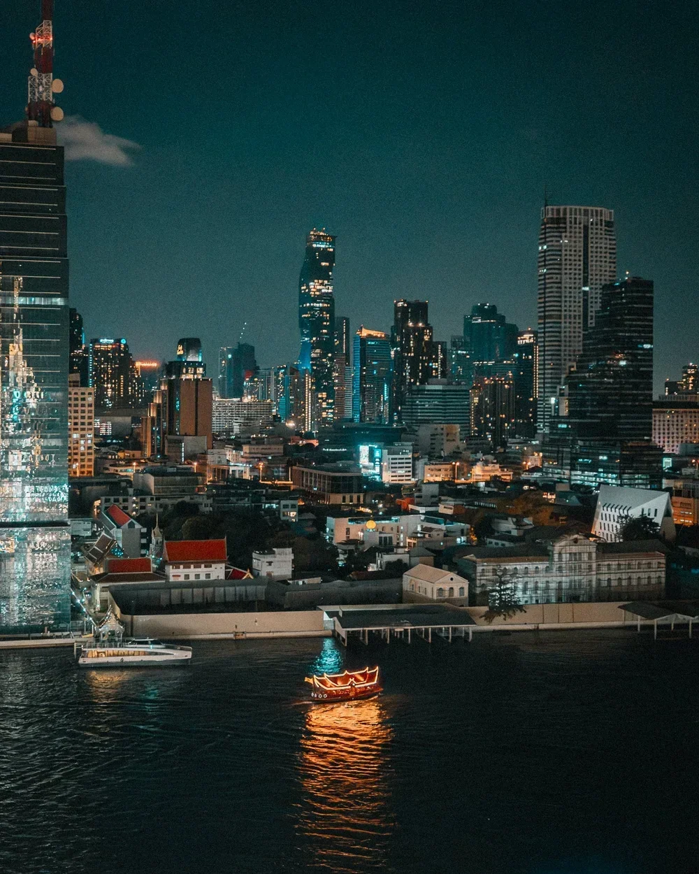 Bangkok skyline and illuminated boat on the river at night