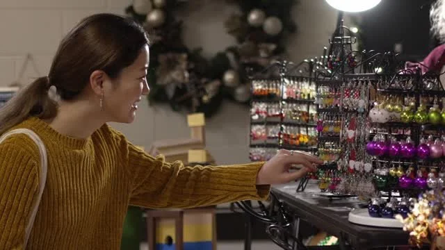 A shopper smiling as she reaches for an ornament at a vendor display.