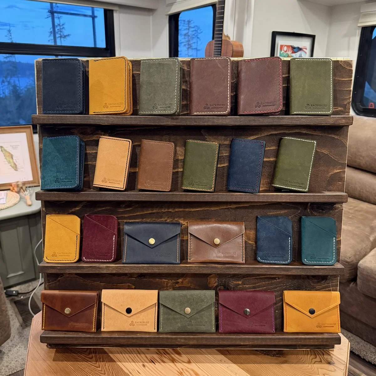 A tiered wooden stand filled with wallets and card holders in green, oxblood, tan, navy and black
