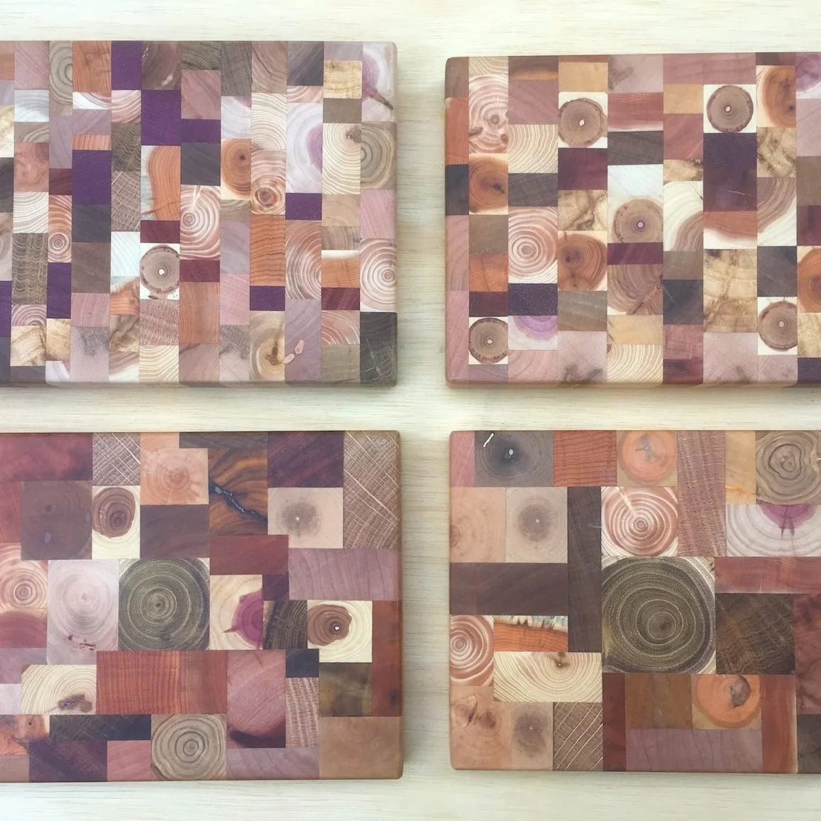 End grain serving boards built from small offcuts of many different woods, in pinks, purples, creams and browns