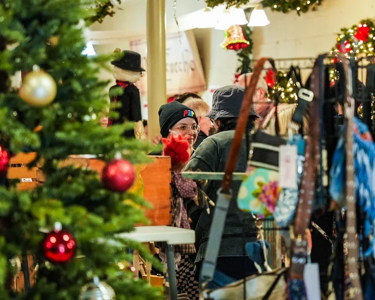 Shoppers chatting beside a decorated Christmas tree.