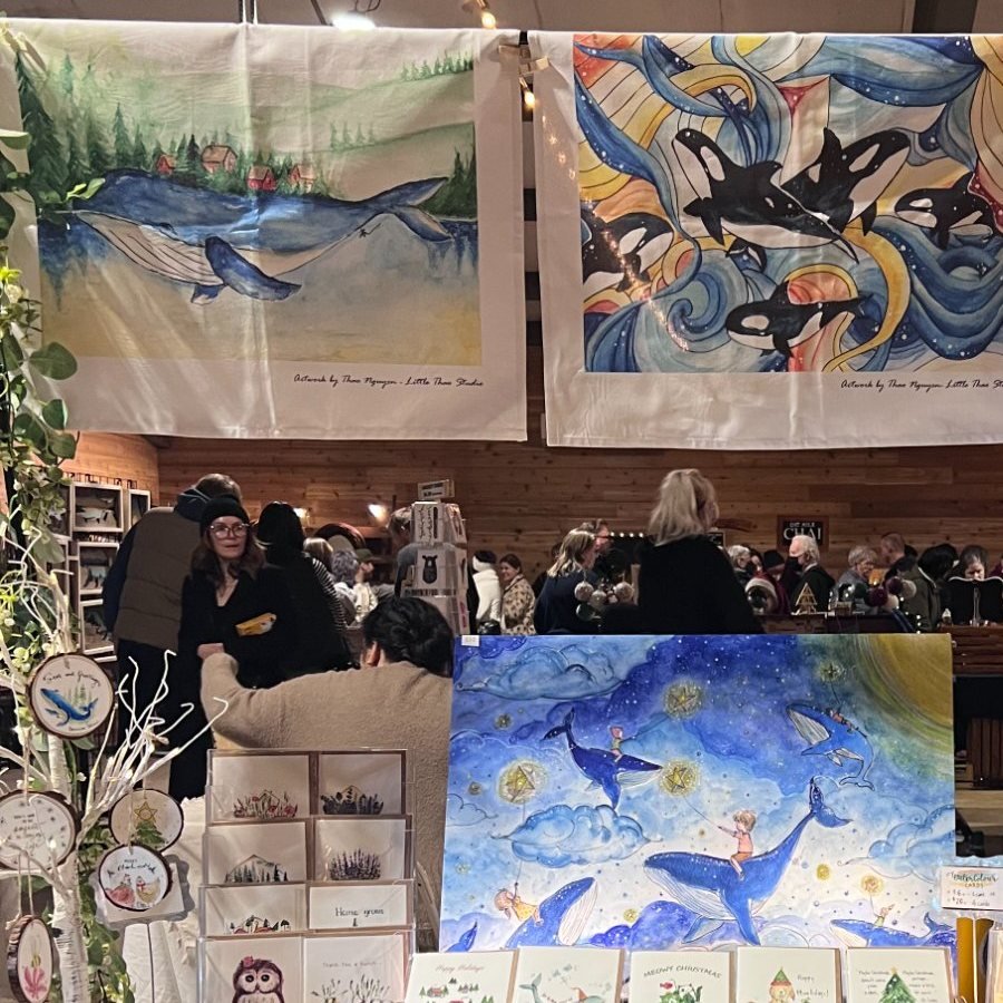 Her market stall, printed tea towels of whales hanging above the table under a string of warm lights