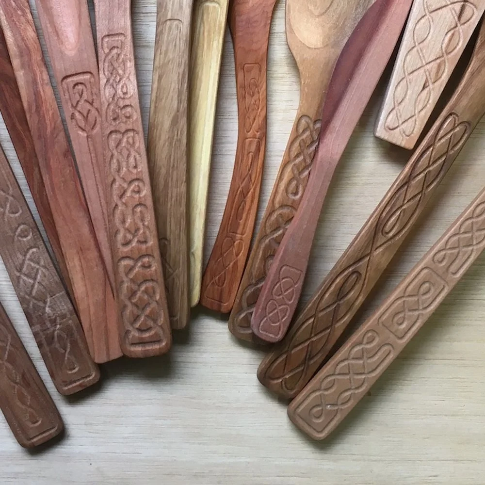 A close view of carved utensil handles, each cut with a different interlaced Celtic knot pattern, in cherry, walnut and pale maple