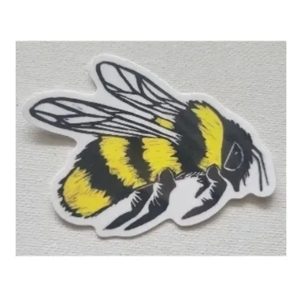 A die-cut vinyl sticker of a bumblebee printed from a linocut, in black and yellow with white wings