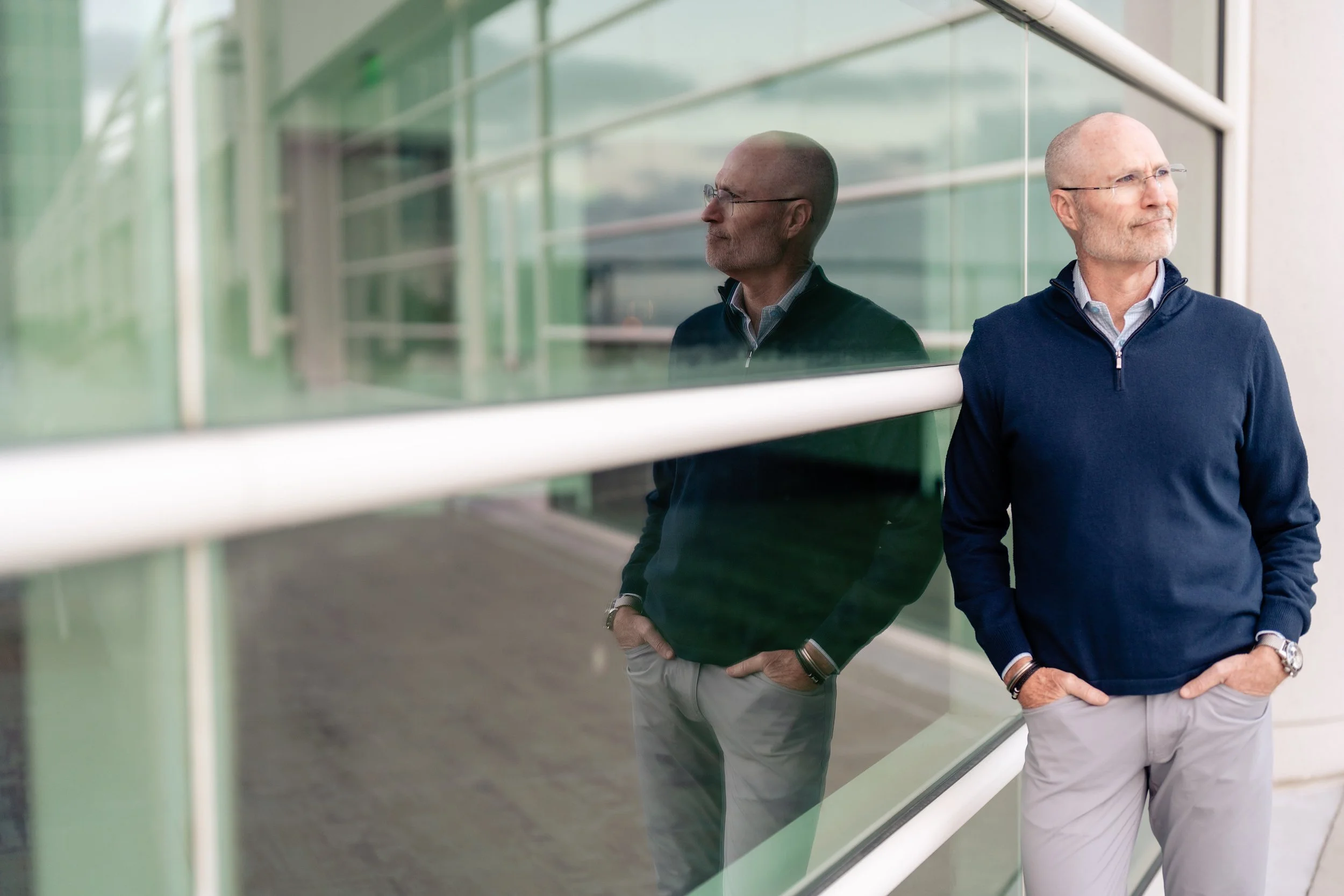 Kirk Michie standing by glass wall, reflective pose