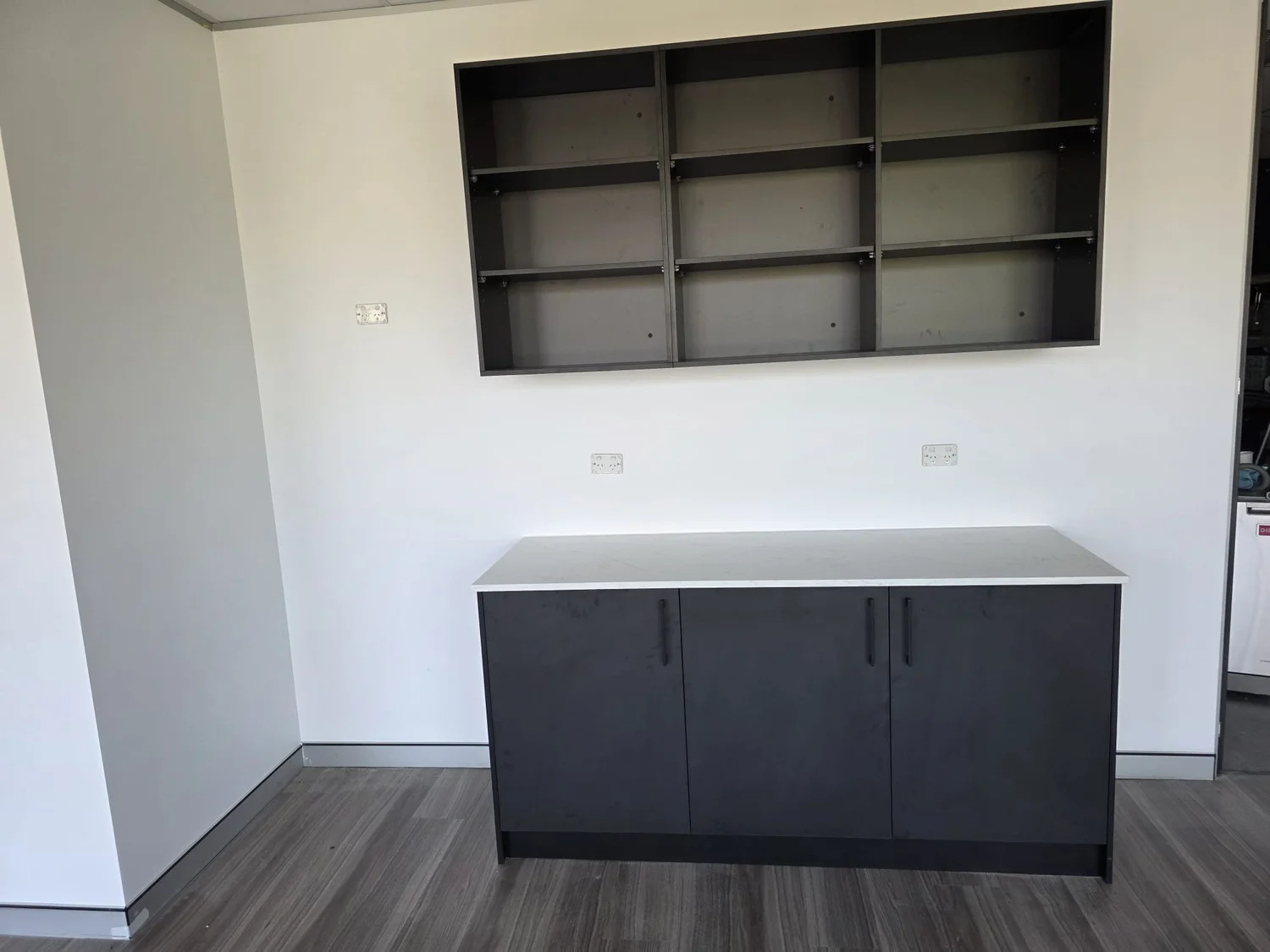 Black credenza with white stone top beneath a black open shelving grid