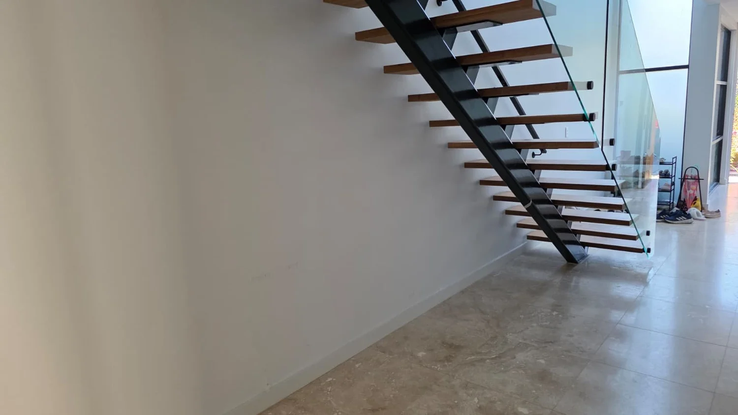 Wide view of the under-stair space showing the open steel staircase and travertine floor