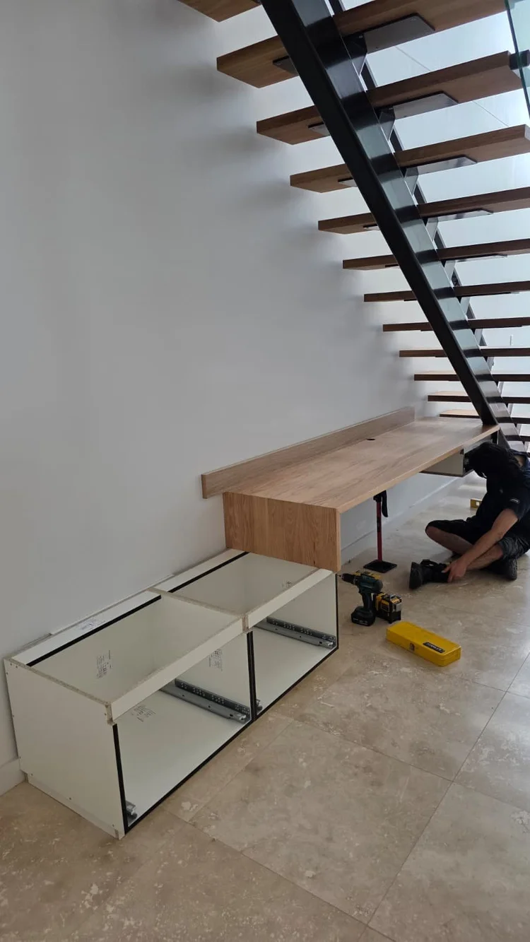 Mid-install: cabinet carcasses open with drawer runners visible, a prop holding the oak top