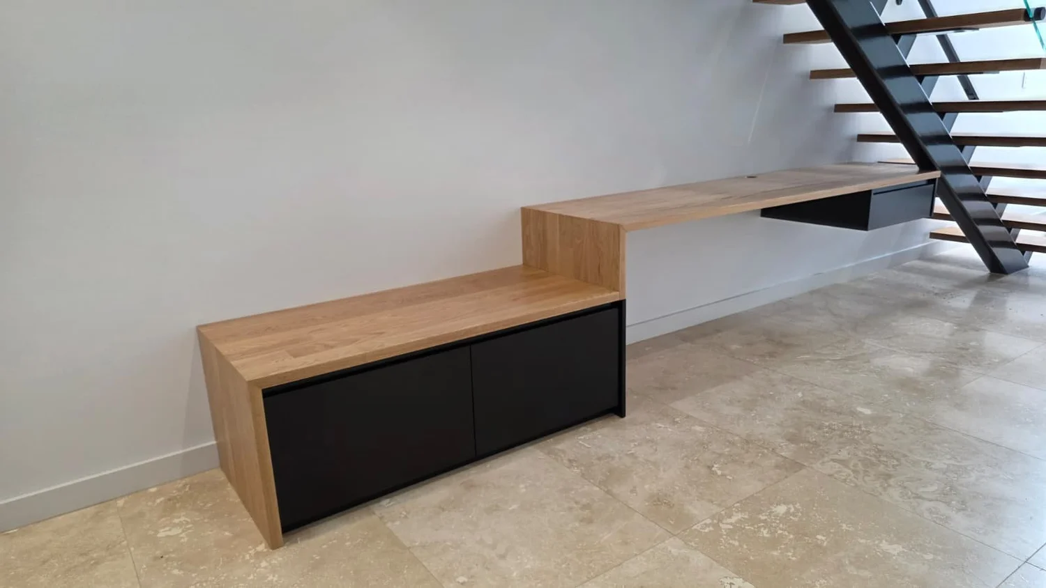 Custom under-stair desk and bench in oak and matt black, built beneath an open steel staircase