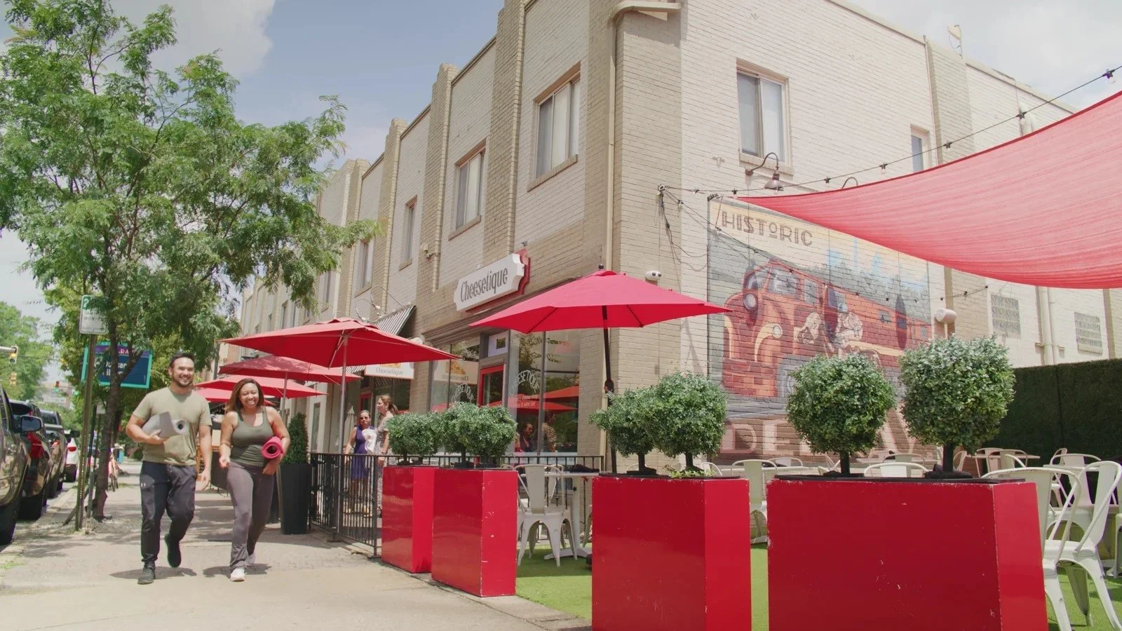 People walk past red outdoor seating and a mural along Mount Vernon Avenue in Del Ray.