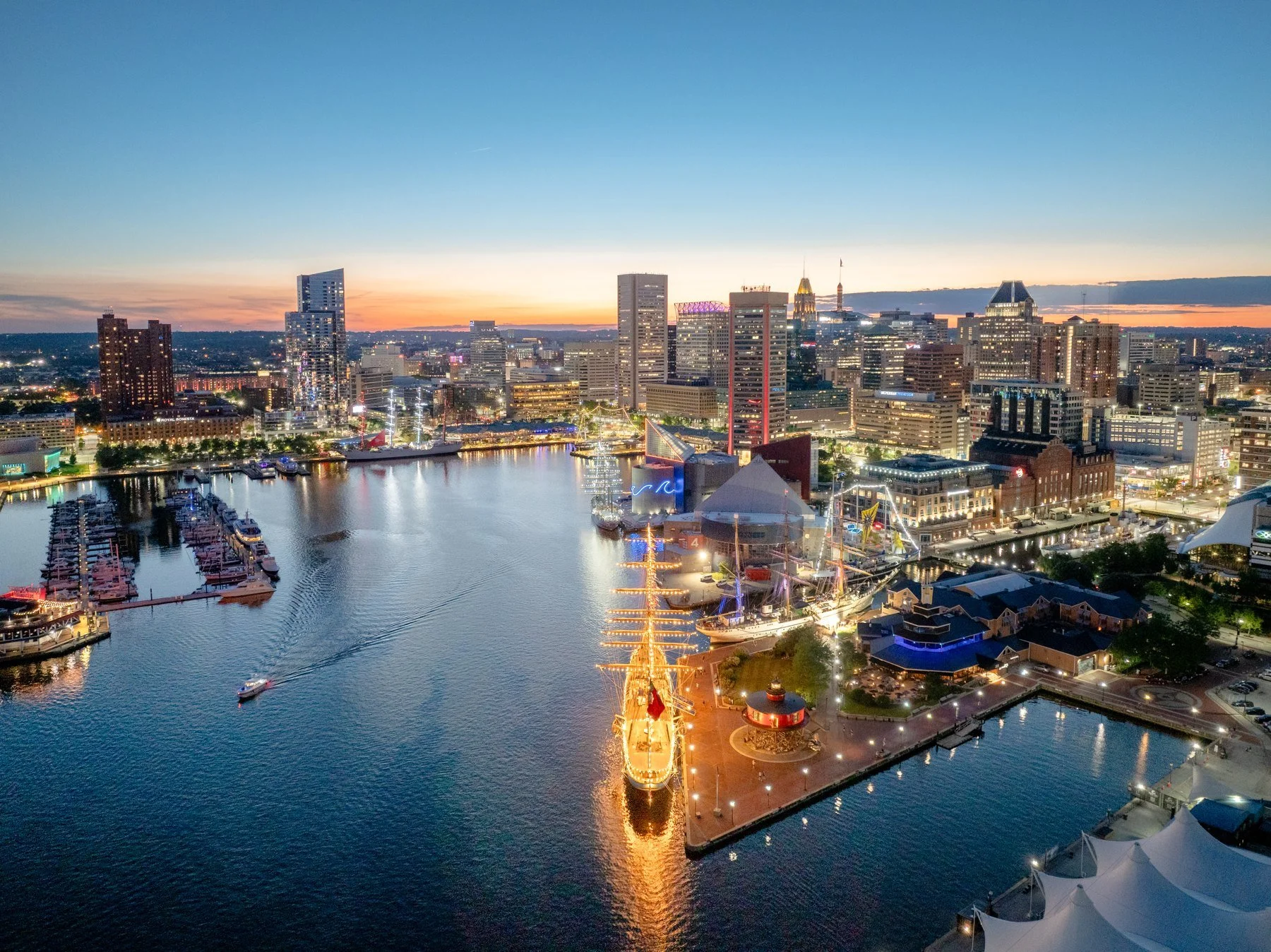 Baltimore’s illuminated Inner Harbor skyline, promenade and waterfront at dusk.