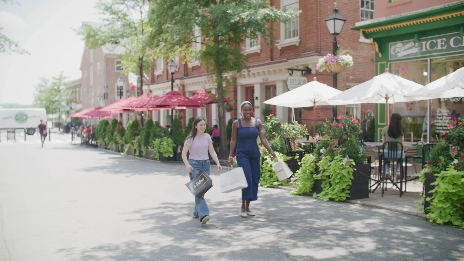 Two people walk with shopping bags along King Street in Old Town Alexandria.