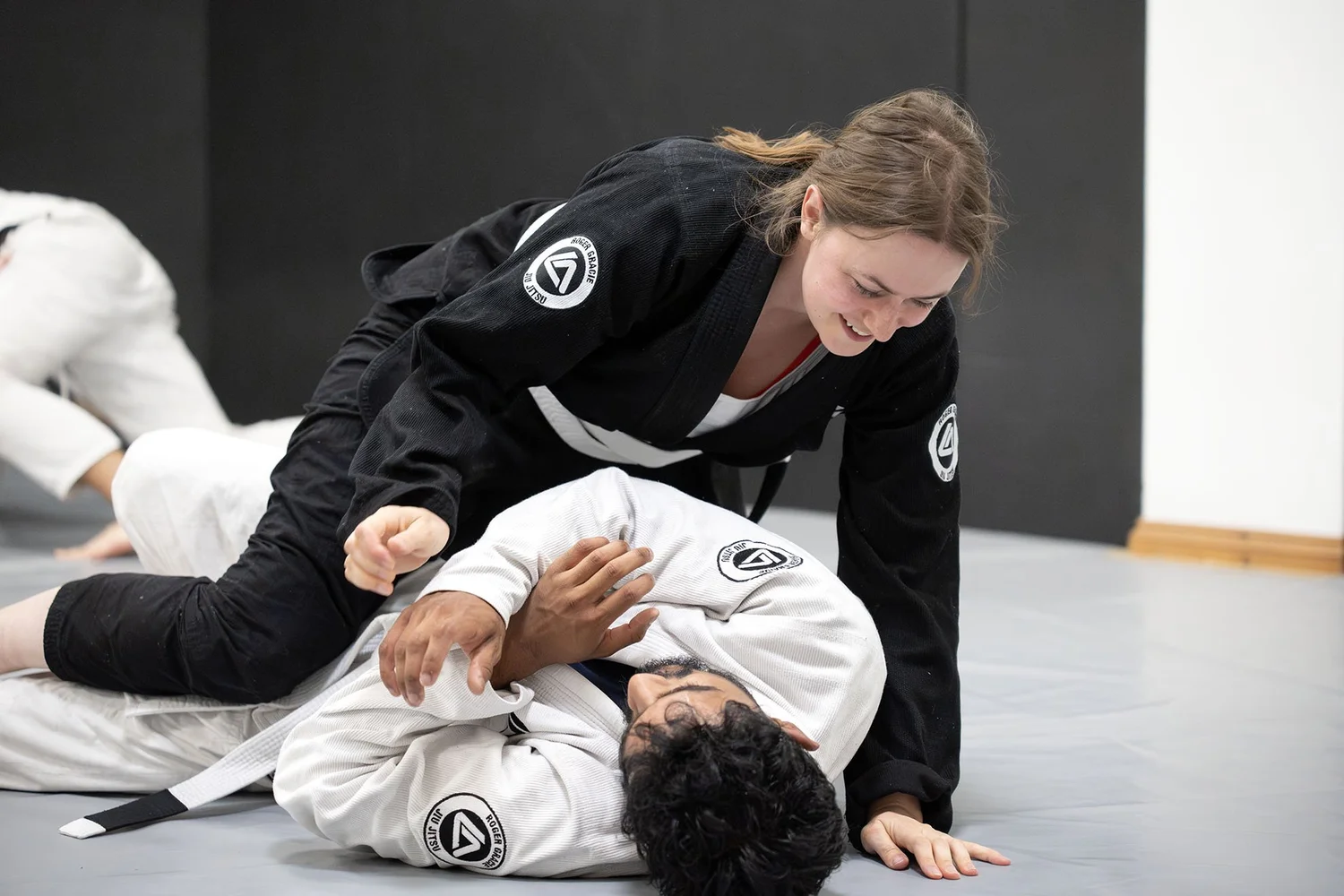 Two students smiling while practising Gi Jiu Jitsu together