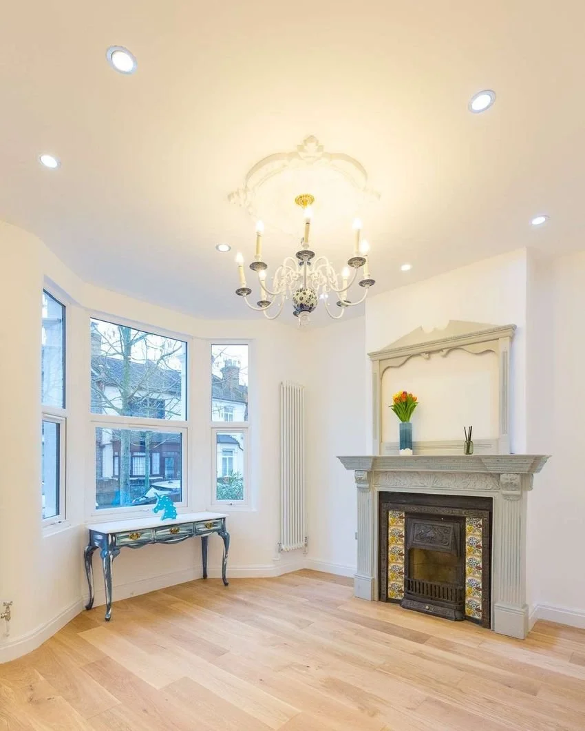The restored living room with duck-egg fireplace surround and Delft chandelier