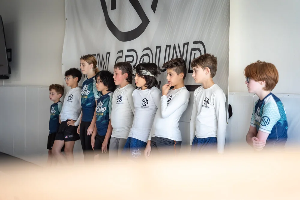 Kids lined up in uniform at the edge of the mat