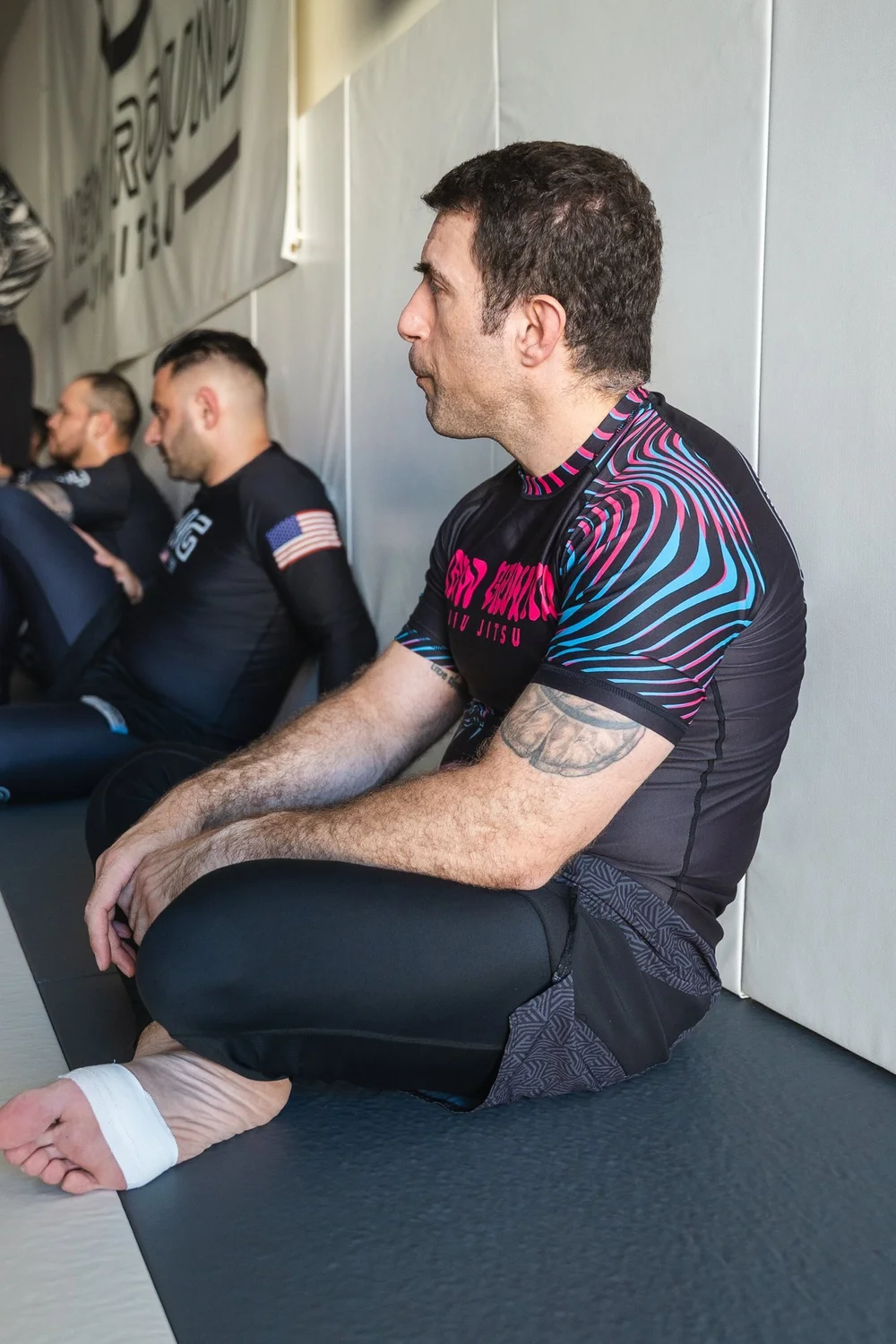 A coach talking one-to-one with a student at the edge of the mat