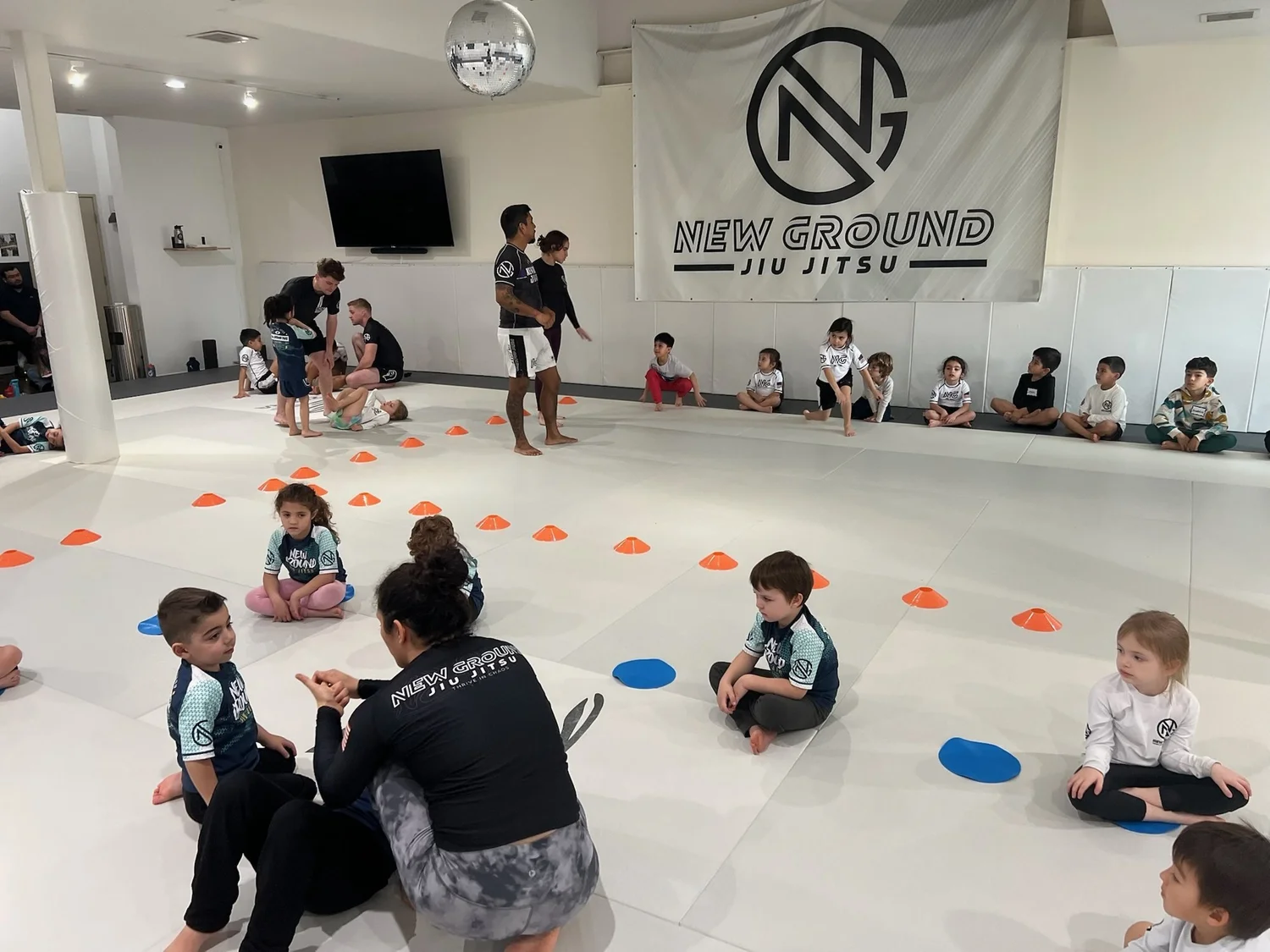 A Little Grounders kids class mid-game with a coach down at their level