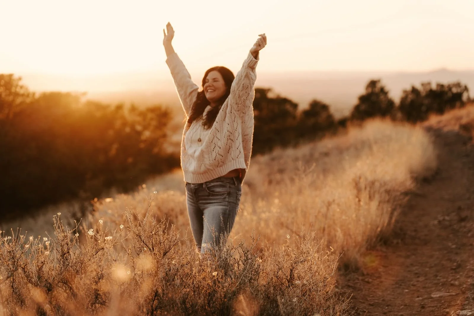 Raechelle with arms raised in a golden field