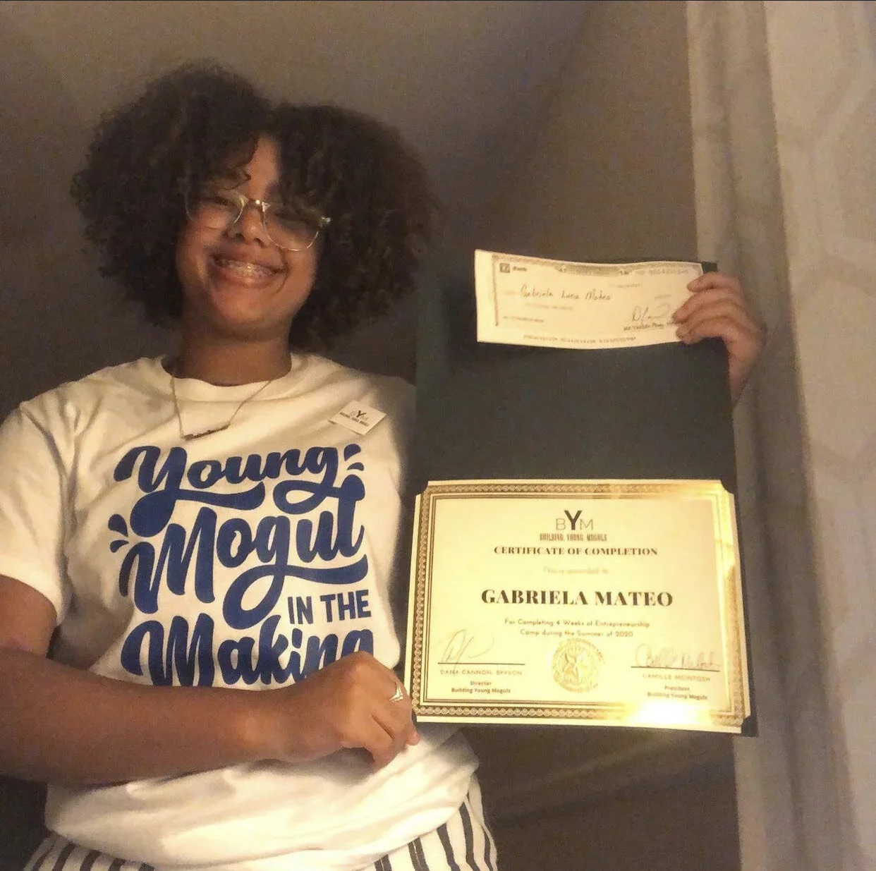 Gabriela Mateo holding her BYM entrepreneurship camp certificate and grant check