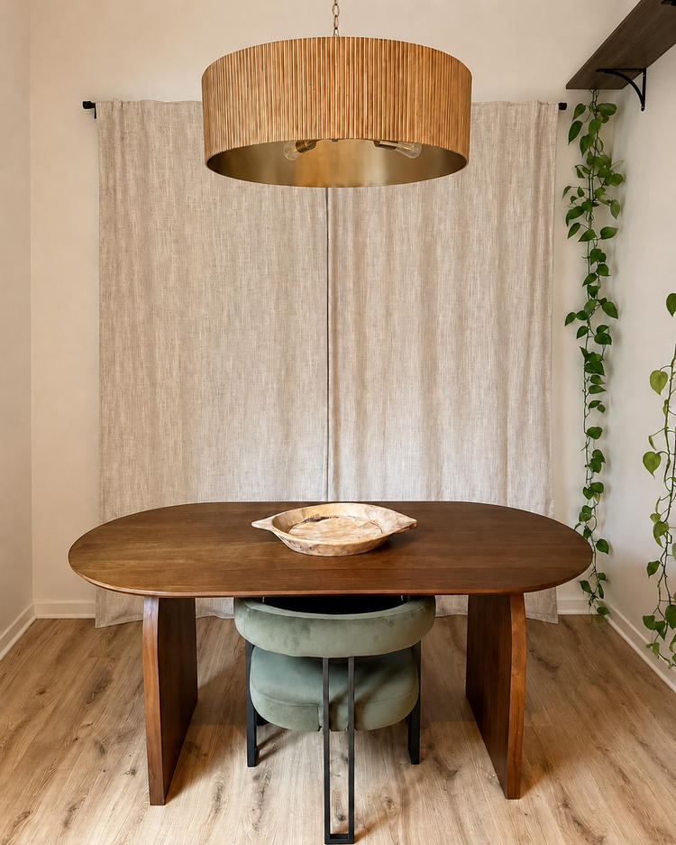 Dining room with a warm wood table, woven brass light fixture and trailing plants