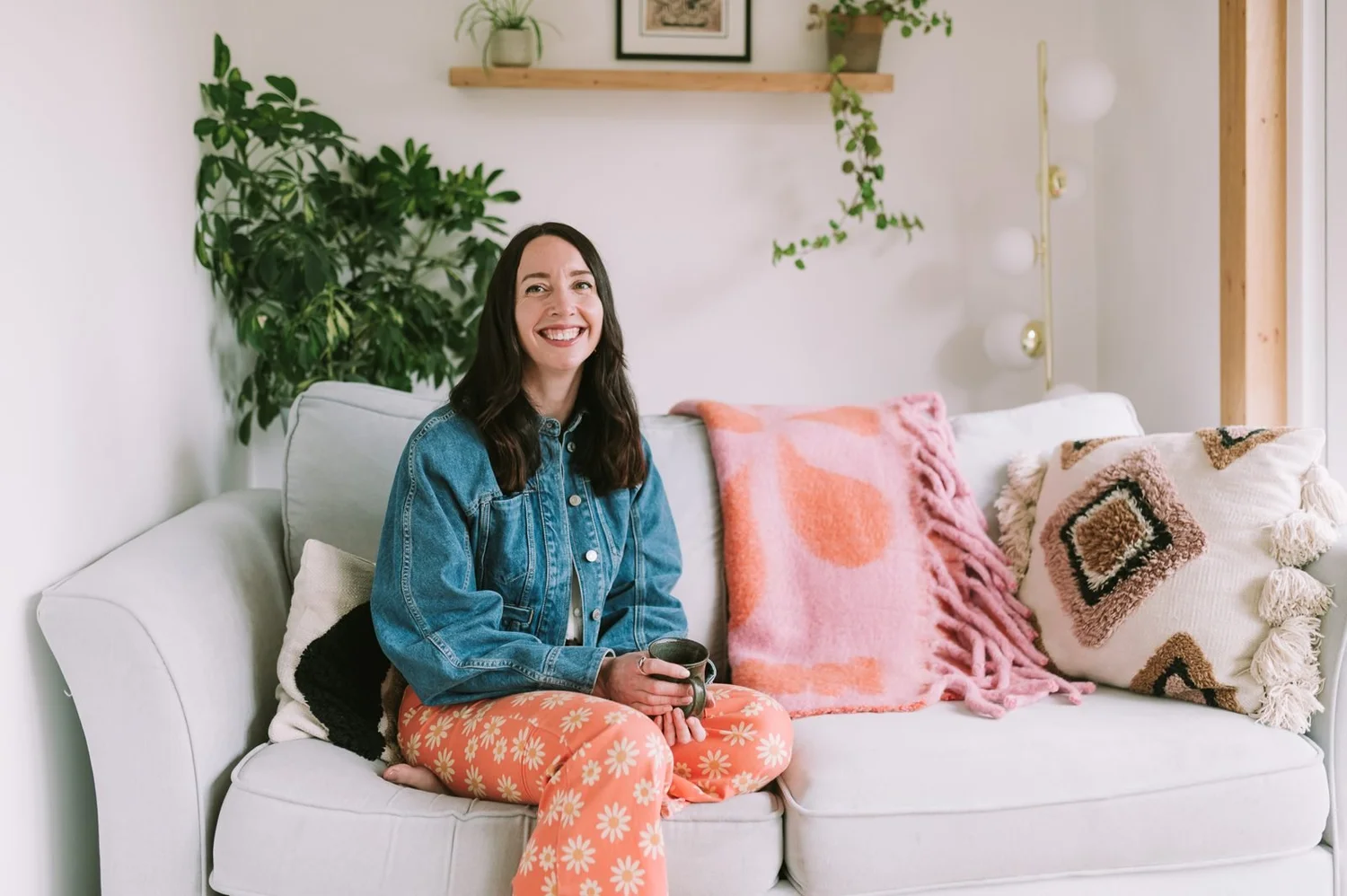 Lauren smiling on her sofa with a cup of tea