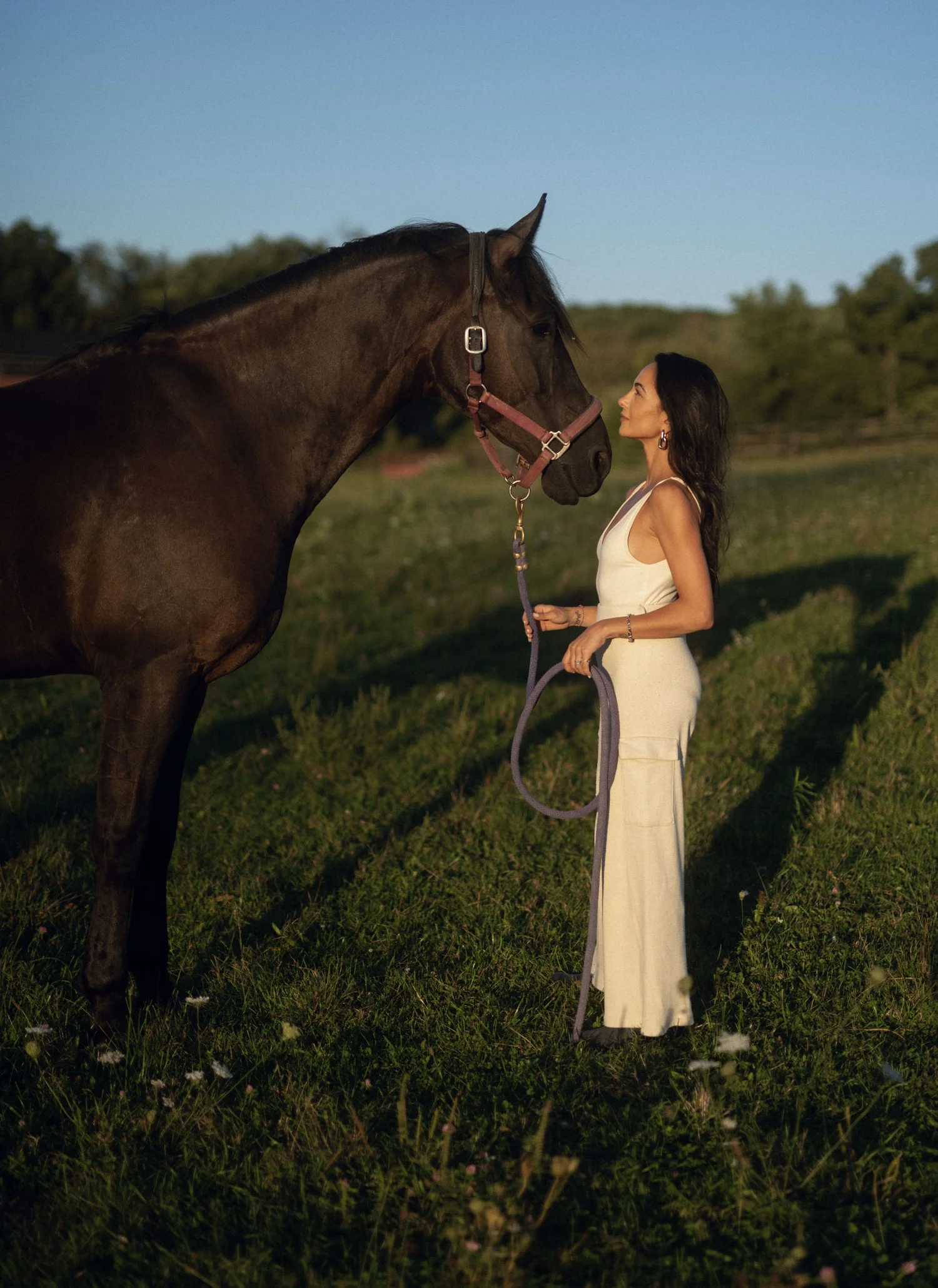 Bee Bosnak in a white dress facing a horse