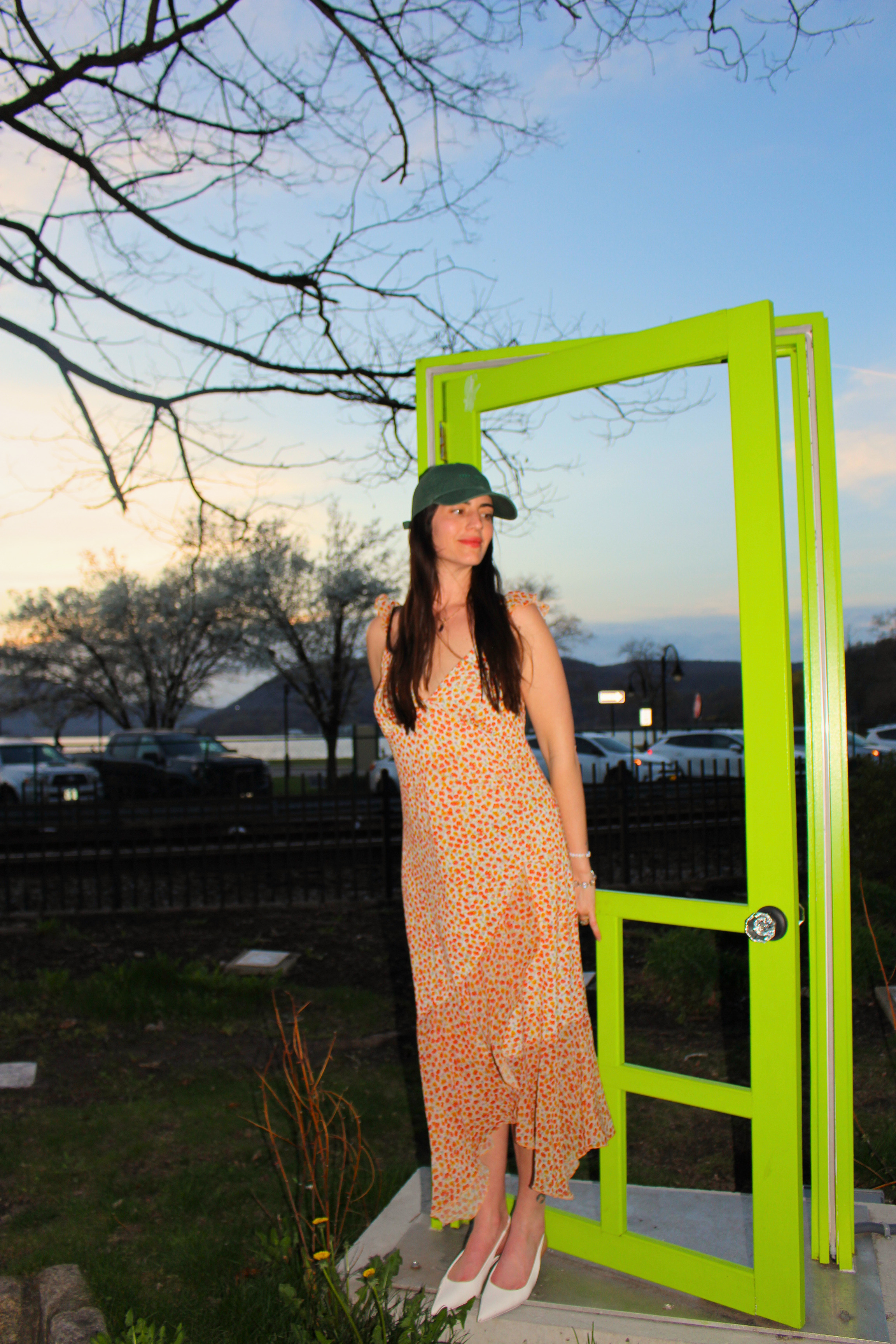 Lisa Littleton standing at a green door in the middle of an open field at golden hour
