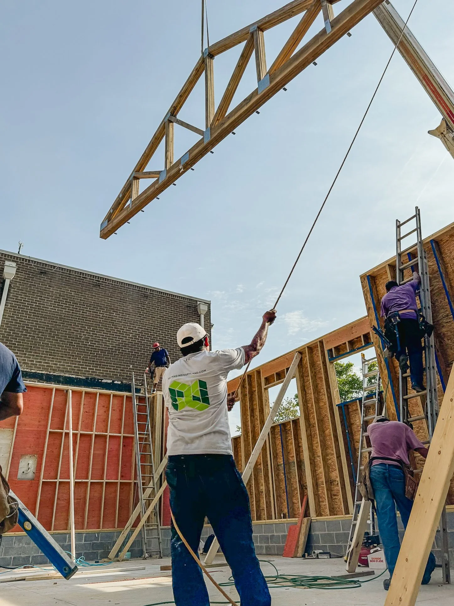Reimagine Remodeling crew guiding a roof truss into place during structural framing