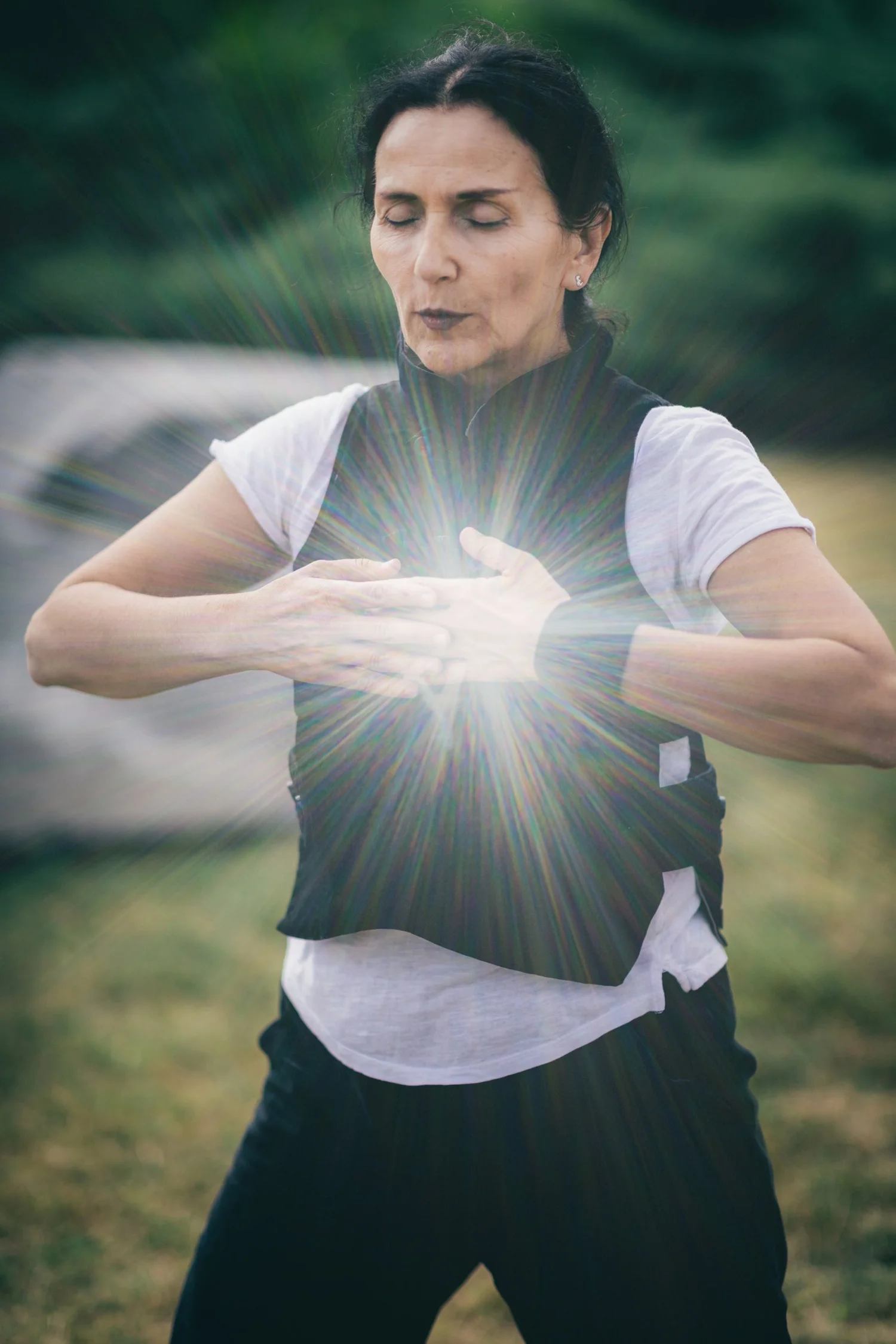 A woman standing outdoors mid-movement, hands open in front of her