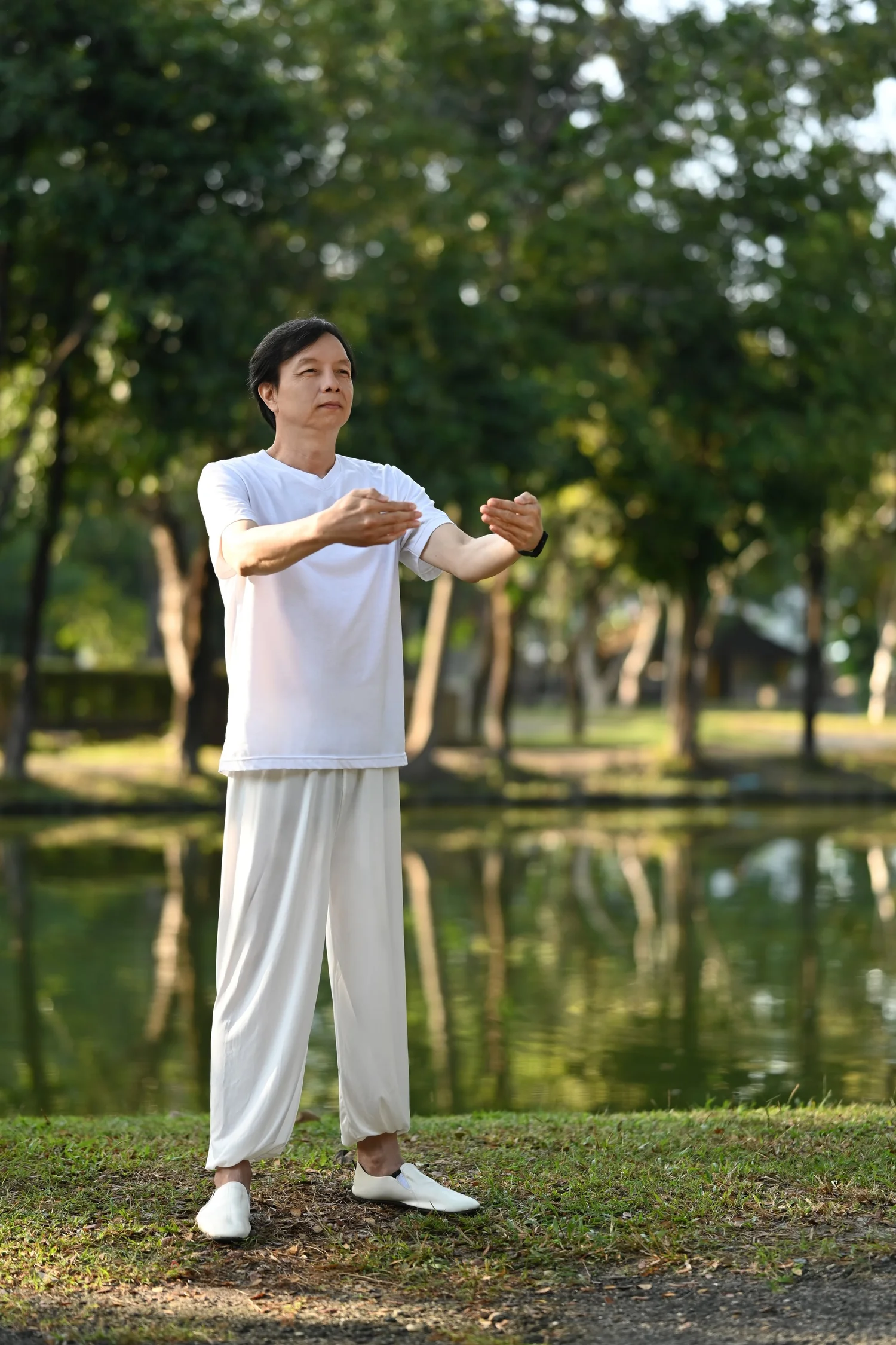 A woman in white practising alone beside still water